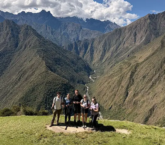 Group of hikers admiring the steep Andean mountains and deep valley on the Inca Trail