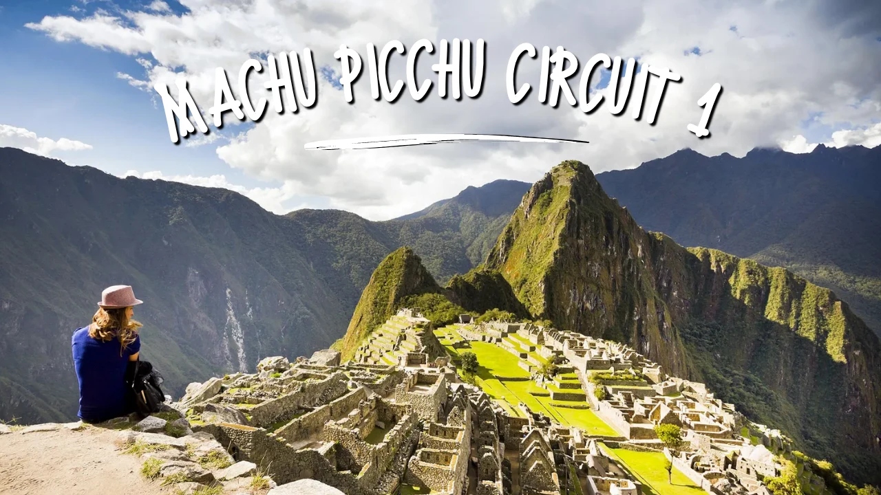 Panoramic view of Machu Picchu from Circuit 1 with a visitor overlooking the Inca citadel and surrounding mountains.